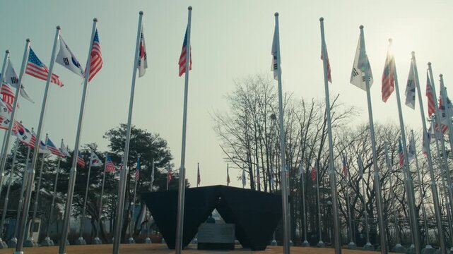 Low-Angle View of UN Forces National Flags Waving on Tall Flagpoles Around a Monument at Imjingak Resort Park Near the DMZ in Paju