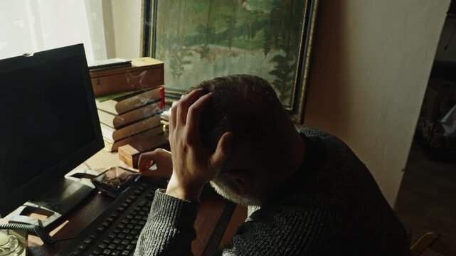 A home worker pauses in frustration while using a vintage computer. Themes of stress, creative block, deadlines, burnout, and workplace pressure are strongly conveyed.