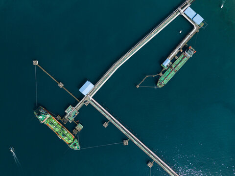 Aerial view of the Oil Fuel Terminal Port with large tanker ships docked at the industrial pier in the deep blue sea, Manggis, Bali, Indonesia.