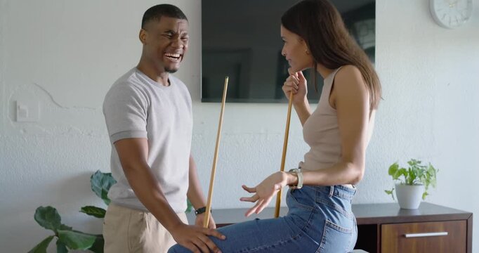 African American couple exchanging flirtatious remark, leaning on red-felt pool table with cues