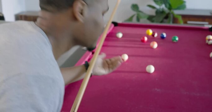 Main player is pulling cue back, striking cue ball on magenta-felt table, aiming to pocket balls