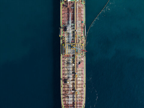 Aerial view of an oil tanker docked at the Oil Fuel Terminal Port, showing the industrial deck structure and pipelines surrounded by deep blue sea in Manggis, Bali, Indonesia.