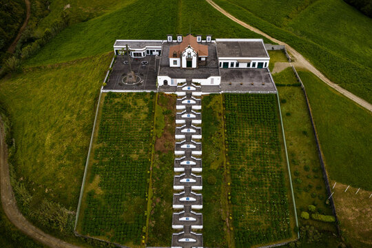 Aerial view of the Chapel of Nossa Senhora da Paz, featuring its iconic staircase and surrounding green hills in Vila Franca Do Campo, Acores, Portugal.