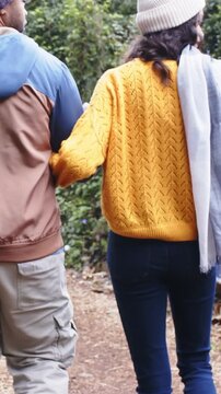 Vertical video: Walking couple wearing jackets on dirt trail, woman entering linking arms leisurely
