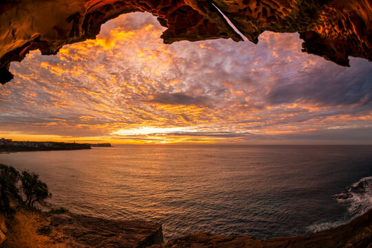 Sunrise illuminates sculpted sandstone cliffs and coastal rock formations overlooking the Pacific Ocean along the Sydney coastline, New South Wales, Australia.