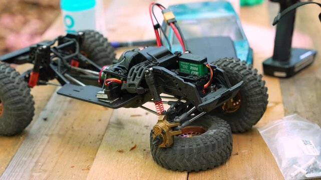 An exposed RC truck chassis balancing on a loose tire to demonstrate high flex suspension articulation.
