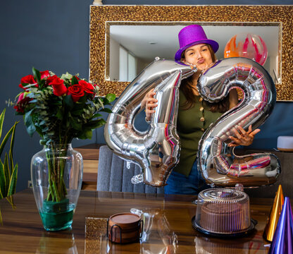 Woman celebrating 42nd birthday holding silver balloons
