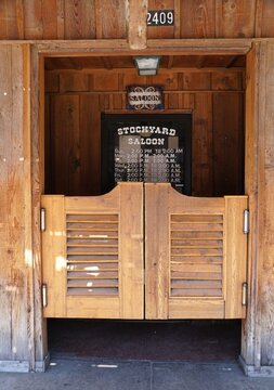 Fort Worth, Texas, U.S.A - June 1, 2026 - Wooden Stockyard Saloon entrance with swinging doors, posted operating hours, and rustic Western-themed exterior.