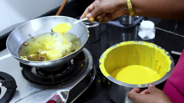 Close-up of batata vada being dipped in gram flour batter and deep fried on stove. Ideal for Indian street food, homemade cooking, traditional recipes and food culture content.