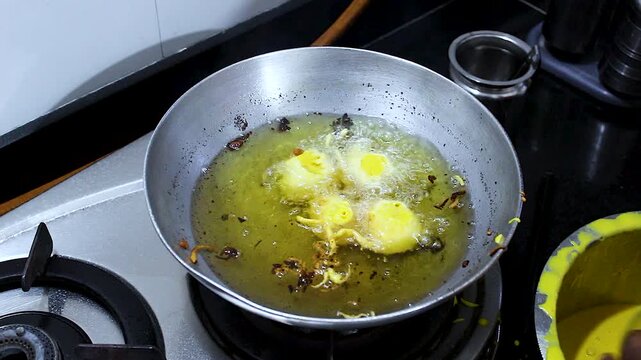 Close-up of batata vada being fried in hot oil during preparation. Perfect for Indian cuisine, street food, cooking tutorials, snack production, and homemade recipe content.
