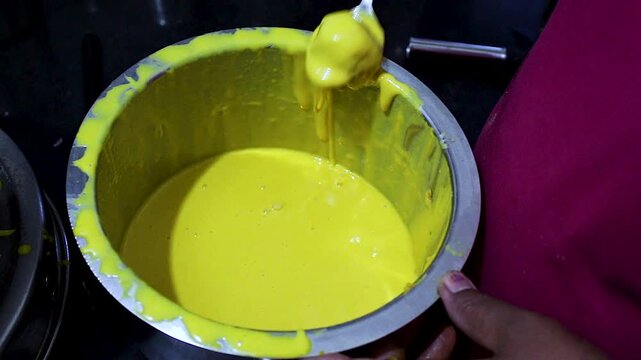 Close-up of potato filling dipped into gram flour batter while preparing batata vada. Ideal for Indian cooking tutorials, street food, homemade snack preparation, and recipe content.