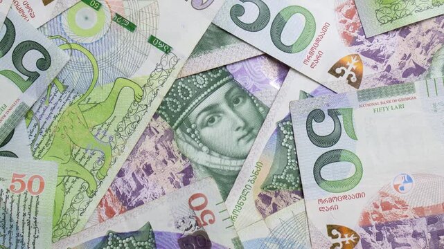 Close up top view video. Green paper banknotes of Georgia. 50 GEL, lari bill. Georgian cash money with female face, Queen Tamara portrait. Concept of pay tax, debt, loan, currency exchange. Bank note