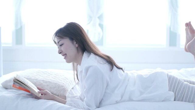 ベッドに寝転び読書する日本人女性