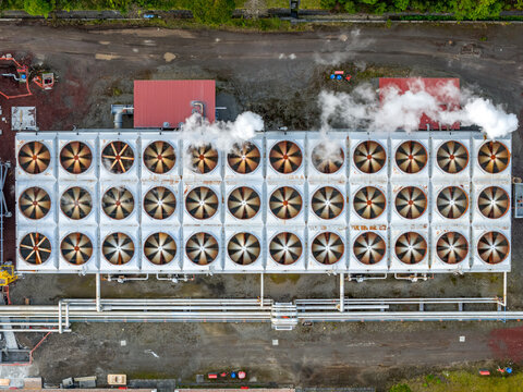Aerial view of the Ribeira Grande Geothermal Power Station featuring rows of cooling fans emitting steam and industrial piping, Ribeira Grande, Acores, Portugal.