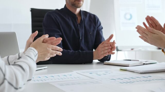 Professional business team clapping hands, celebrating successful presentation, displaying collaborative spirit and workplace enthusiasm in modern office setting
