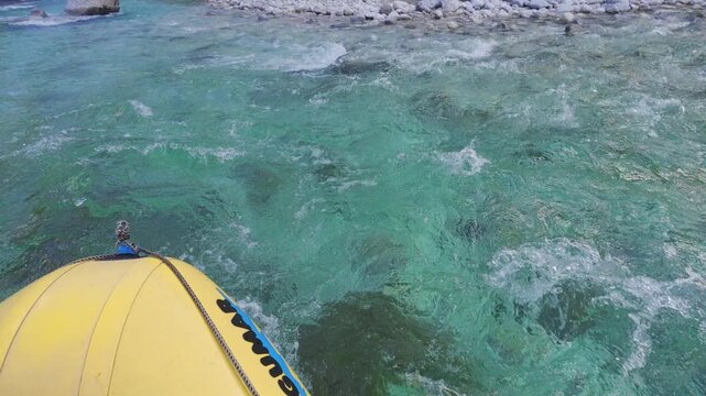 Rafting paddler POV on fast flowing Soca River with rocky banks and forested mountains, navigating rocky portions