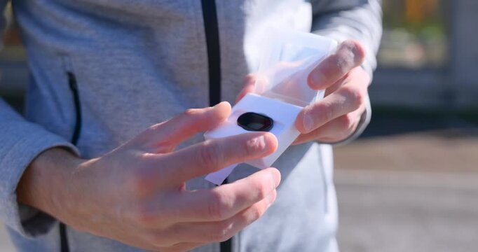 Hands unboxing of filter for 70mai dashcam outdoors. Close-up