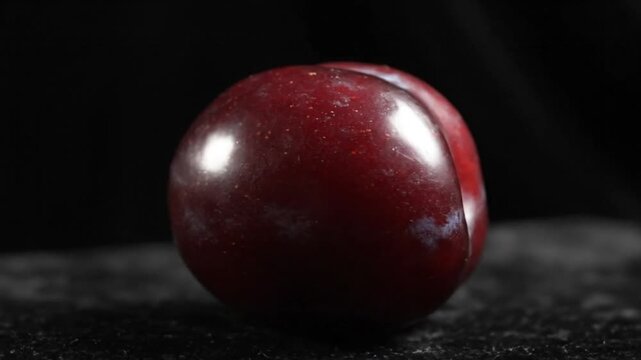 Ripe and Shiny Plum Fruit Against a Dark Backdrop Shows Smooth Texture and Freshness in Studio Lighting