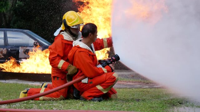Firefighter fighting with flame using fire hose chemical water foam spray engine. Fireman wear hard hat, body safe suit uniform for protection. Rescue training in fire fighting extinguisher