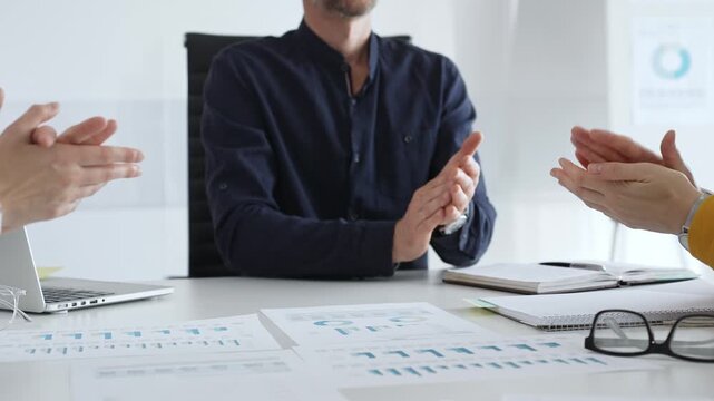 Businessman shaking hands with female partner over workplace documents, symbolizing collaborative spirit and shared workplace success. Business concept