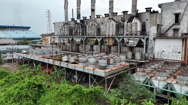A drone shot showing a row of cylindrical metal cooling units on an industrial platform at an old diesel power plant. 