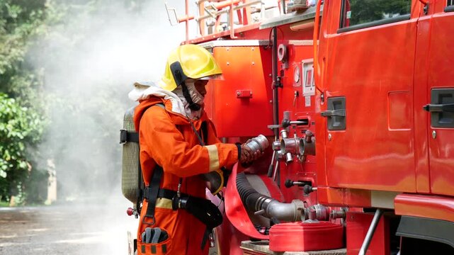 Firefighter fighting with flame using fire hose chemical water foam spray engine. Fireman wear hard hat, body safe suit uniform for protection. Rescue training in fire fighting extinguisher