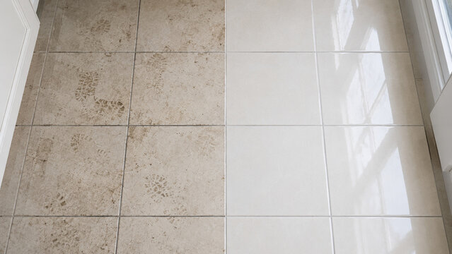 A tiled floor showing a clear contrast between dirty, muddy tiles on the left and clean, shiny tiles on the right under natural light.