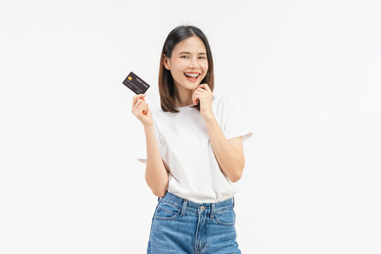 Happy young Asian woman holding credit cards with a confident smile isolated on white studio background.