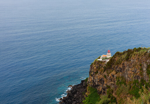 Farol do Arnel. Lighthouse on a steep Atlantic cliff near Nordeste. Ocean expanse fills the background. Sao Miguel, Azores, Portugal.