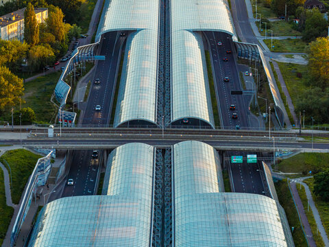 Aerial view of glass noise barriers covering a multi-lane highway with cars driving through the city of Warszawa, Mazowieckie, Poland.