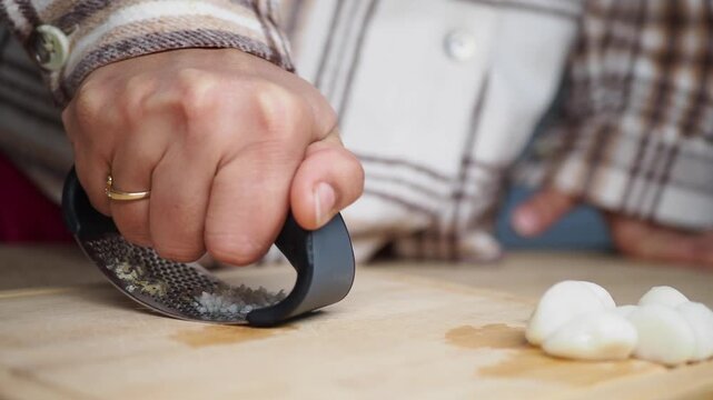 Chopping garlic on a wooden cutting board in the kitchen