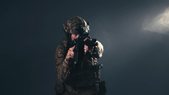 Camouflaged soldier aiming rifle while wearing protective combat equipment. Concept battlefield readiness, military service and security.
