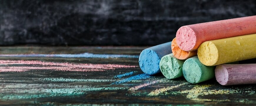 Colorful chalks stacked on a blackboard with vibrant streaks of chalk marks everywhere