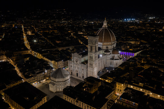 Aerial view of the illuminated Cathedral of Santa Maria del Fiore surrounded by historic city rooftops in Firenze, Toscana, Italy.