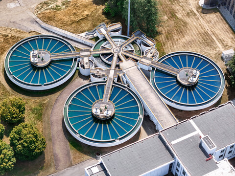 Aerial view of the SMAT water purification plant featuring large circular sedimentation tanks with turquoise water and interconnected walkways in Torino, Piemonte, Italy.