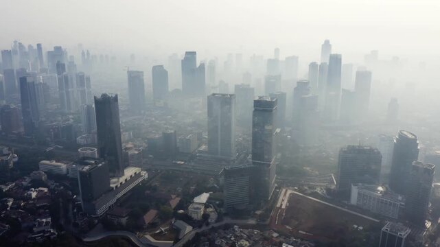 High-angle aerial view of a metropolitan city skyline shrouded in dense morning fog and smog.