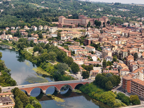 Aerial view of the historic Moncalieri Castle overlooking the Po River, with its stone bridge and surrounding town rooftops in Moncalieri, Piedmont, Italy.