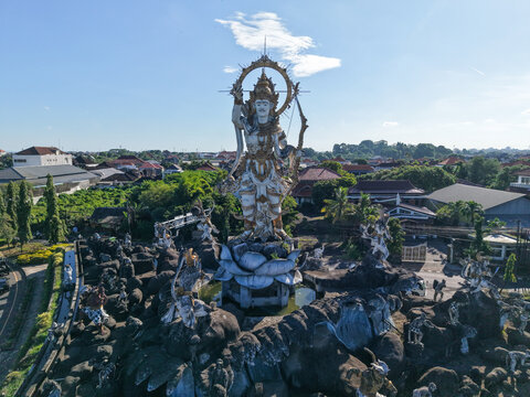 Aerial view of the Patung Titi Banda statue featuring Lord Rama on a lotus base amidst a rocky landscape in Kecamatan Denpasar Timur, Bali, Indonesia.