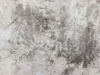 Obraz premium A close-up shot captures the rough, weathered texture of an old concrete wall. The surface is uneven, dark patches, mineral stains, and reflecting natural aging