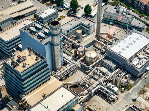 Aerial view of Centrale Termoelettrica - Moncalieri power plant with industrial buildings, tall chimneys, and complex piping systems in Moncalieri, Piemonte, Italy.