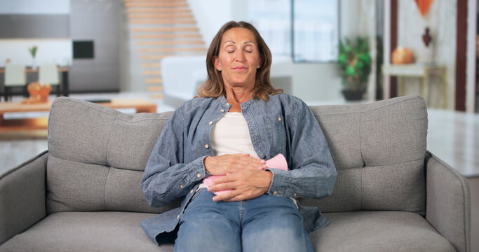 Mature Woman Sits Quietly At Home Holding Lower Abdomen