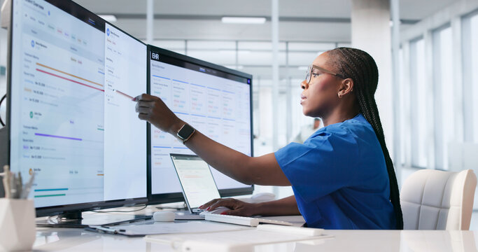 Young Female Healthcare Worker Reviews Patient Records On Laptop