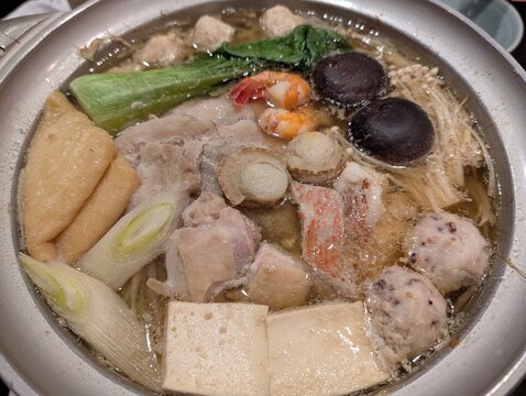 Japanese chanko nabe hot pot with chicken, seafood, tofu, mushrooms and vegetables simmering in a metal pot