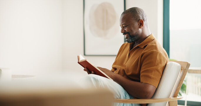 Reading, relax and smile of black man on chair in home living room for fable or fiction. Space, book and literature story with mature person in apartment for break, fantasy tale or hobby on weekend