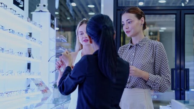 Fashionable women exploring eyewear options in a contemporary optical shop with a helpful sales representative
