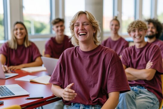 A cheerful group of colleagues in matching mauve shirts laughing together around a red table for workplace culture and modern team concepts