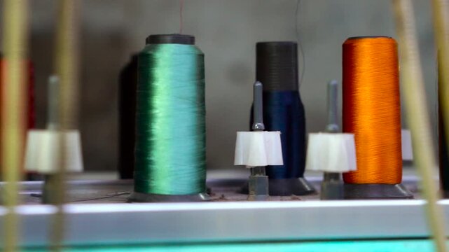 Colorful thread spools arranged on industrial embroidery equipment machine yarn textile factory bobbin
