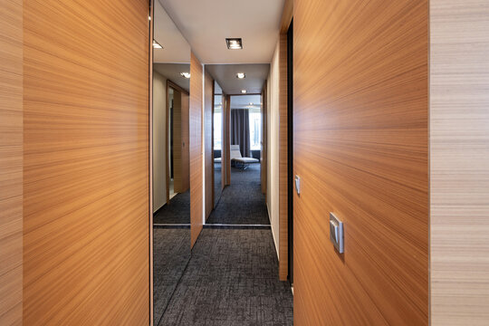 Modern luxury hotel corridor with wooden wall panels and mirrors