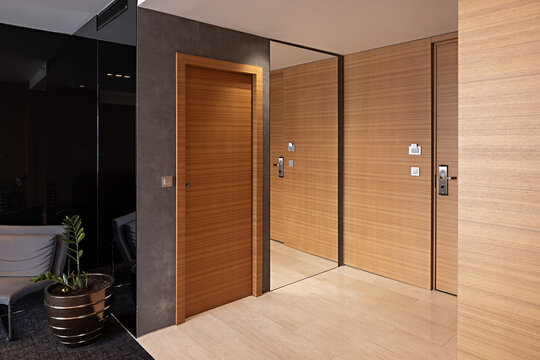 Elegant hotel room entrance with seamless wooden doors and stone floor