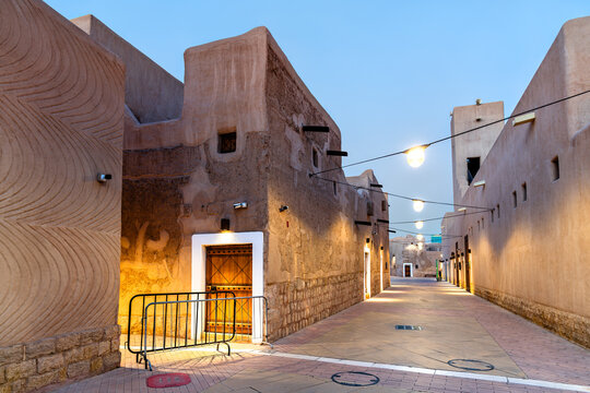 A beautifully lit traditional clay and mud brick alleyway in the historic Al Doho district of Riyadh, Saudi Arabia at dusk